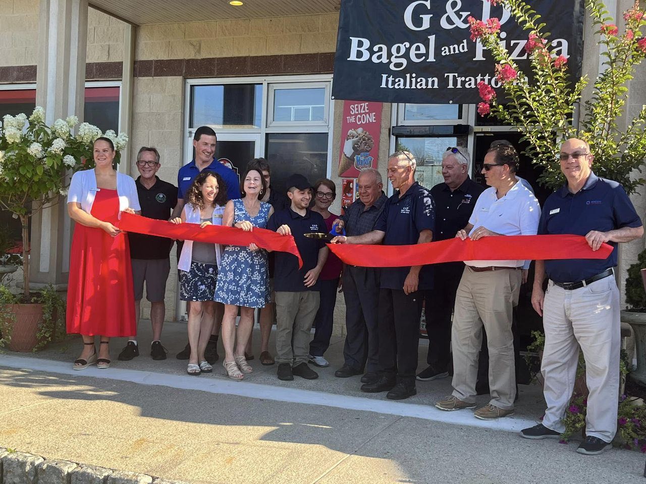 Group of people outside a restaurant performing a ribbon cutting ceremony